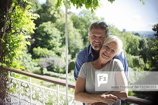 Portrait happy couple hugging on sunny summer balcony