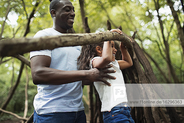 Father and daughter playing with branch in woods