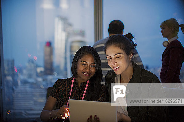 Lächelnde Geschäftsfrauen mit digitalem Tablet arbeiten spät im Büro