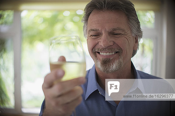 Close up smiling senior man drinking white wine