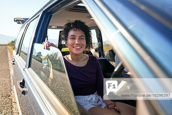 Happy young woman enjoying road trip inside car