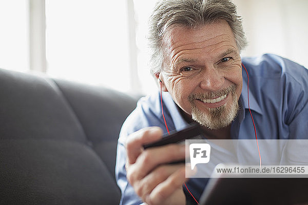 Portrait smiling senior man with headphones and credit card