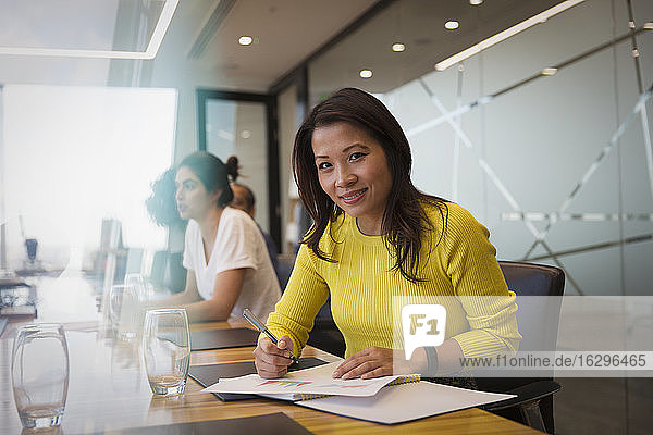 Portrait smiling businesswoman with paperwork in conference room meeting