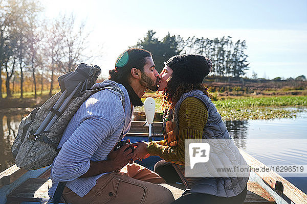 Zärtliches junges Paar küsst sich im Ruderboot auf einem sonnigen Herbstsee