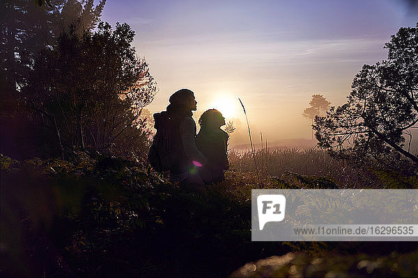 Silhouette eines ruhigen jungen Paares  das bei Sonnenuntergang eine Wanderung in der Natur genießt
