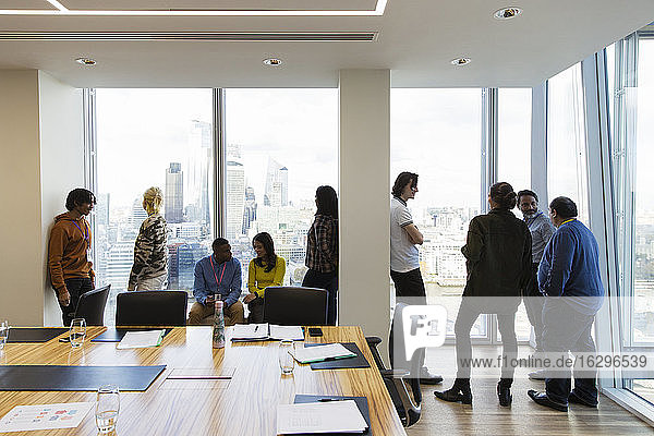 Business people talking at highrise conference room windows