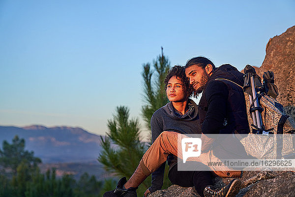Gelassenes junges Wanderpaar geniesst Sonnenuntergang auf Felsen