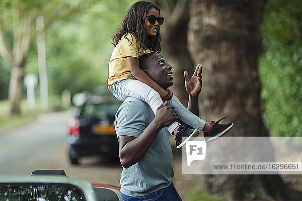 Vater trägt Tochter auf den Schultern im Park