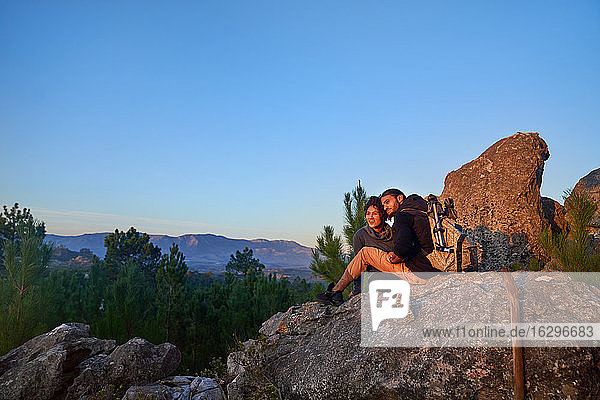 Junges Wandererpaar entspannt sich am Felsen und geniesst den Sonnenuntergang