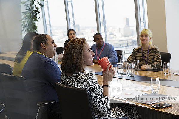 Smiling businesswoman drinking coffee in conference room meeting
