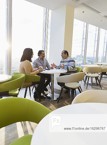 Geschäftsleute unterhalten sich in sonniger Büro-Cafeteria