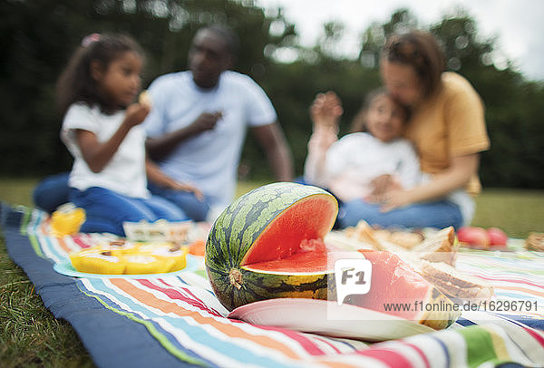 Familie genießt frische Wassermelone auf einer Picknickdecke im Park
