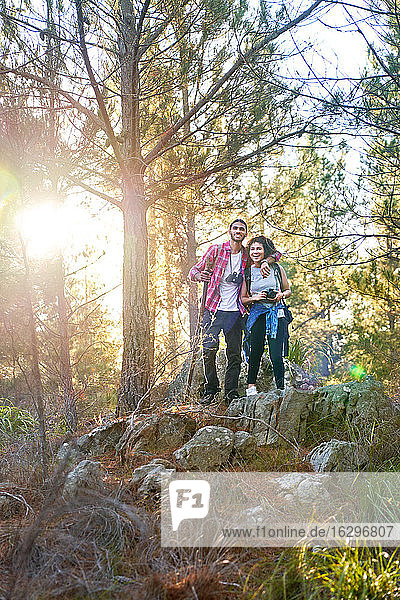 Happy young couple hiking in sunny woods