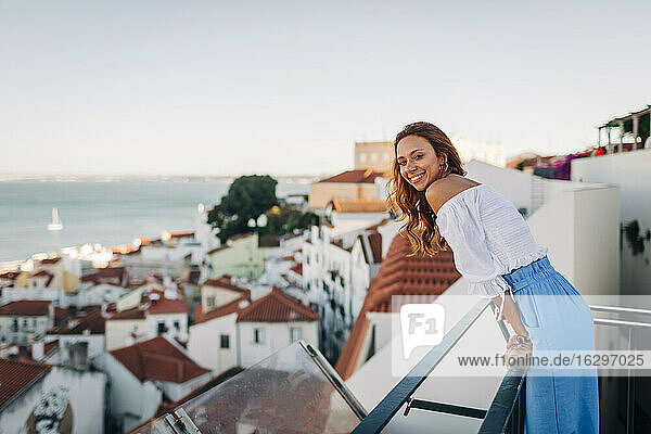 Junge Frau lächelt  während sie auf dem Dach der Alfama  Lissabon  Portugal steht