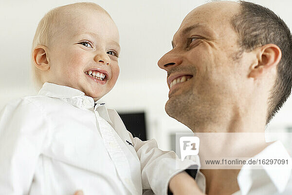 Vater lächelt  während er einen kleinen Jungen ansieht  während er zu Hause steht