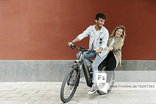 Happy couple enjoying ride on electric bicycle in city