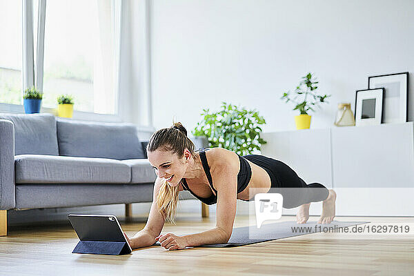 Smiling woman learning plank exercise on internet at home
