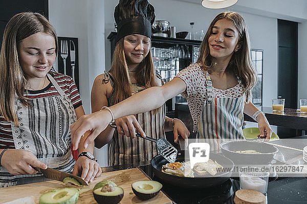 Girlfriends preparing healthy lunch together  frying eggs in kitchen