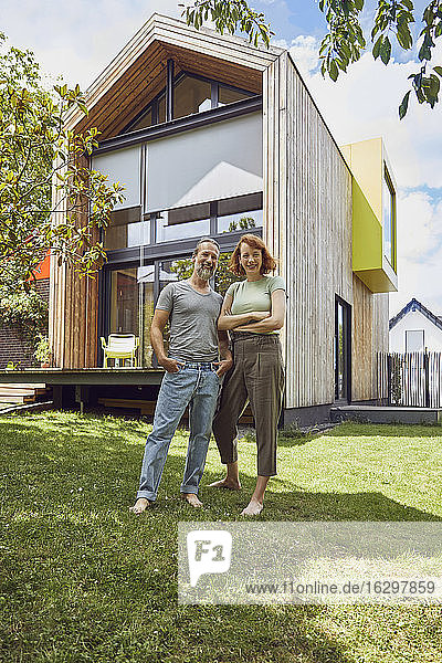 Glückliches Paar  das vor einem kleinen Haus posiert