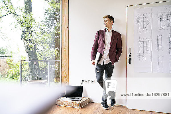 Handsome businessman contemplating while looking through window in office