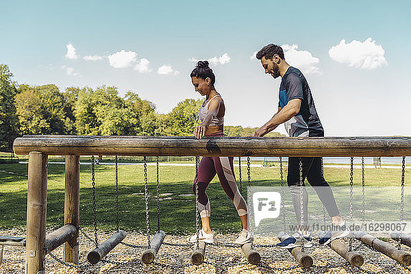 Mann und Frau gehen auf Balancierstämmen auf einem Fitnessparcours