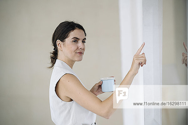Geschäftsfrau  die auf eine Glaswand zeigt  während sie im Büro steht