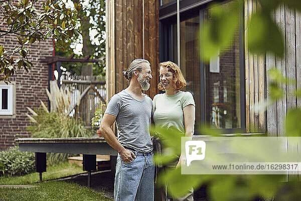Cheerful couple looking at each other while standing in front of tiny house