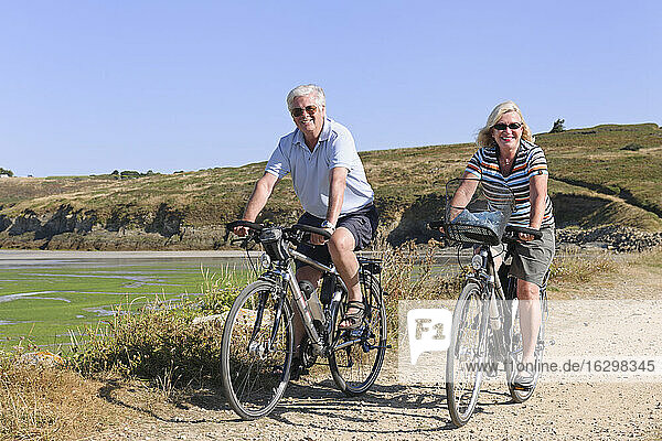 Frankreich  Bretagne  Finistere  Seniorenpaar auf E-Bikes an der Küste