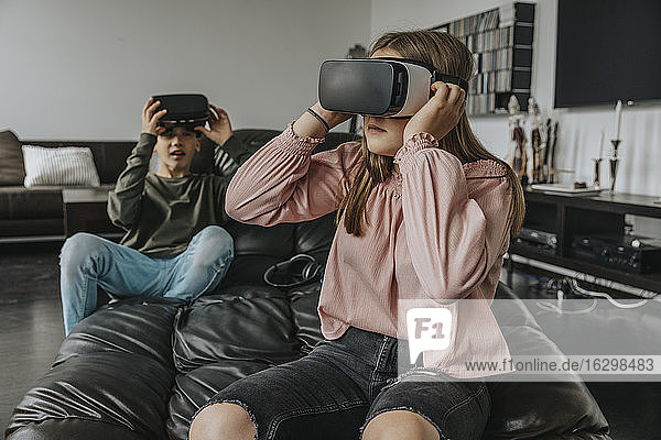 Freunde  die zu Hause auf der Couch sitzen und durch Virtual-Reality-Simulatoren schauen