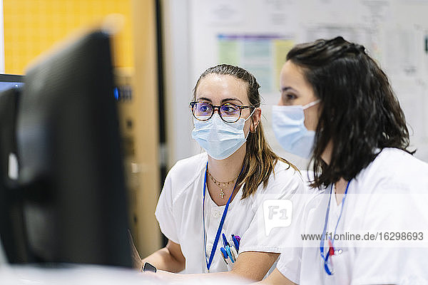 Close-up of female doctors wearing masks using computers in hospital