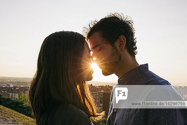 Mann und Frau küssen sich  während sie vor einem klaren Himmel stehen