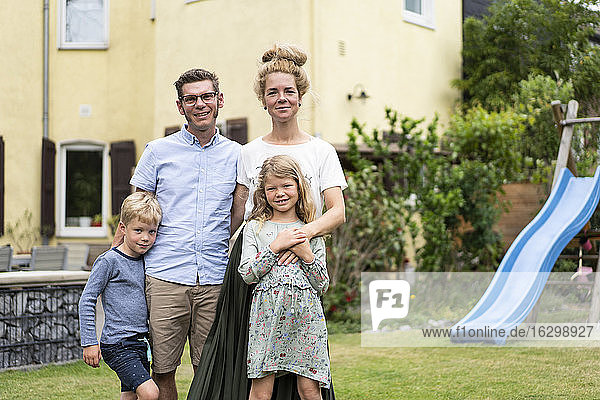 Lächelnde Familie steht im Hinterhof vor dem Haus