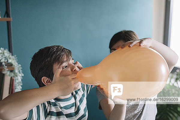 Nahaufnahme eines Mädchens  das seinem Bruder beim Aufblasen eines Luftballons zu Hause hilft
