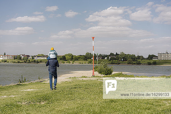 Vater  der seine Tochter auf der Schulter trägt  mit Blick auf den Rhein