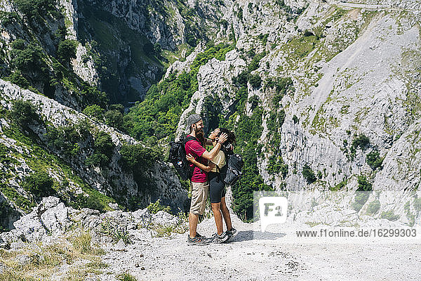 Young man embracing woman while standing on mountain at Ruta Del Cares  Asturias  Spain