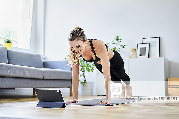 Frau lernt zu Hause mit Hilfe eines digitalen Tablets Übungen im Internet