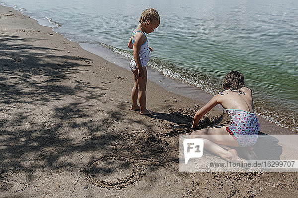 Junge Mädchen spielen im Sand während der Sommerferien am Strand