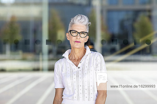 Senior woman standing on street during sunny day