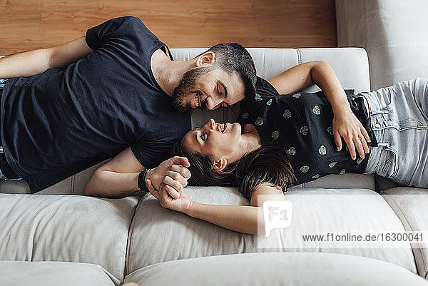 Couple relaxing while lying down on sofa at home