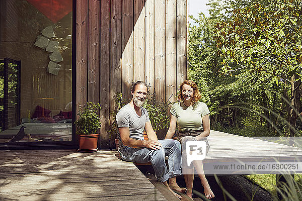Lächelndes Paar  das sich vor einem kleinen Haus entspannt