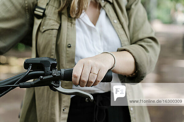 Young woman holding handlebar of electric bicycle