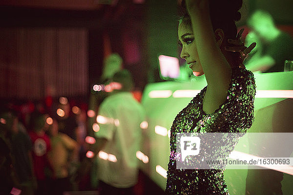 Beautiful woman standing with arms raised in club