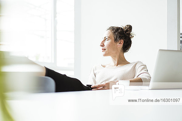 Thoughtful businesswoman with laptop on table