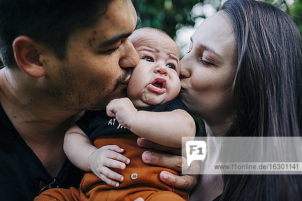 Junge Eltern küssen ihren kleinen Sohn