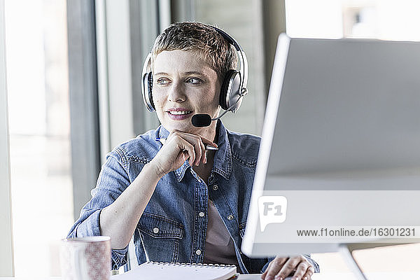 Businesswoman wearing headset at desk in office