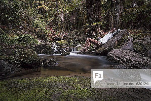 Neuseeland  Whakapapa-Gebiet  Tupapakurua-Wasserfälle  Mann liegt am Bach