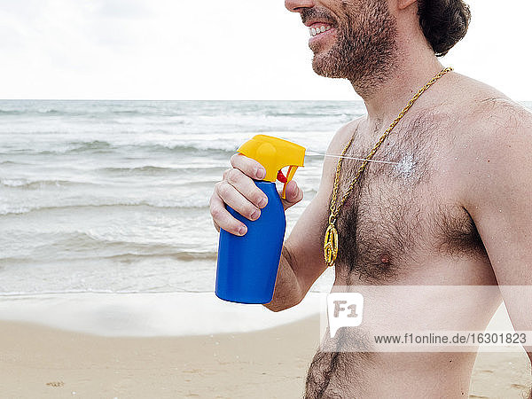 Smiling man applying suncream at beach
