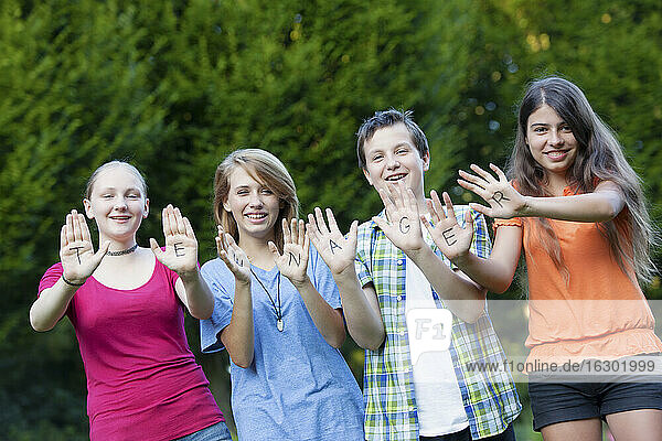 Drei Mädchen und ein Junge zeigen zusammen das Wort Teenager auf ihren Handflächen