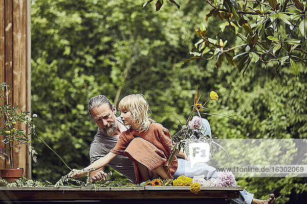 Älterer Mann liegt bei seiner Tochter und arrangiert Blumen im Garten
