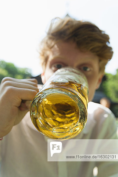 Junger Mann trinkt Bier im Freien